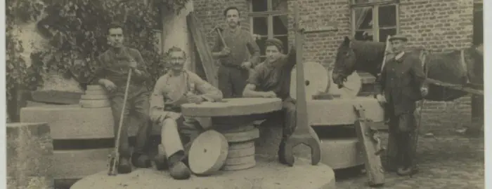 Männer sitzen auf Schleifsteinen der Römermühle, 1912