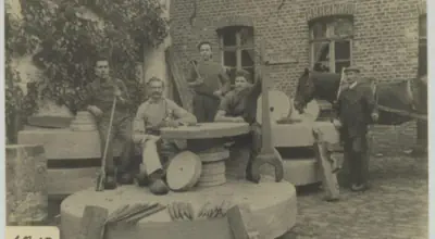 Männer sitzen auf Schleifsteinen der Römermühle, 1912